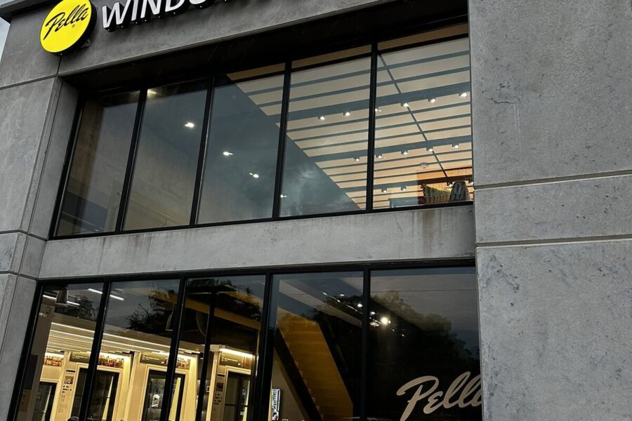 A modern storefront with large windows displays the Pella logo and the words “WINDOWS & DOORS” above the entrance.